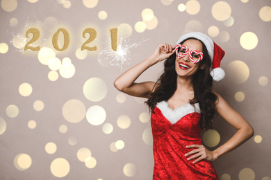 Beautiful woman in Christmas costume with party glasses on beige background. Bokeh effect
