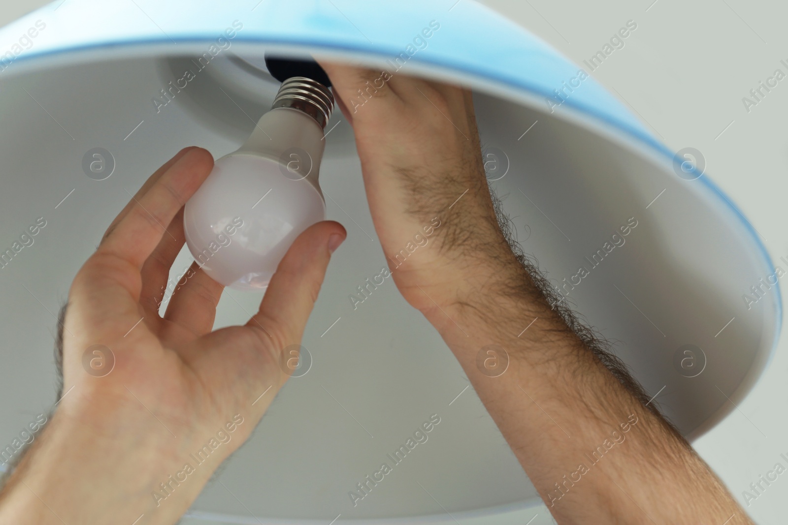 Photo of Man changing light bulb in lamp, closeup