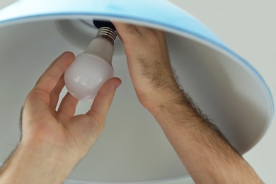 Man changing light bulb in lamp, closeup