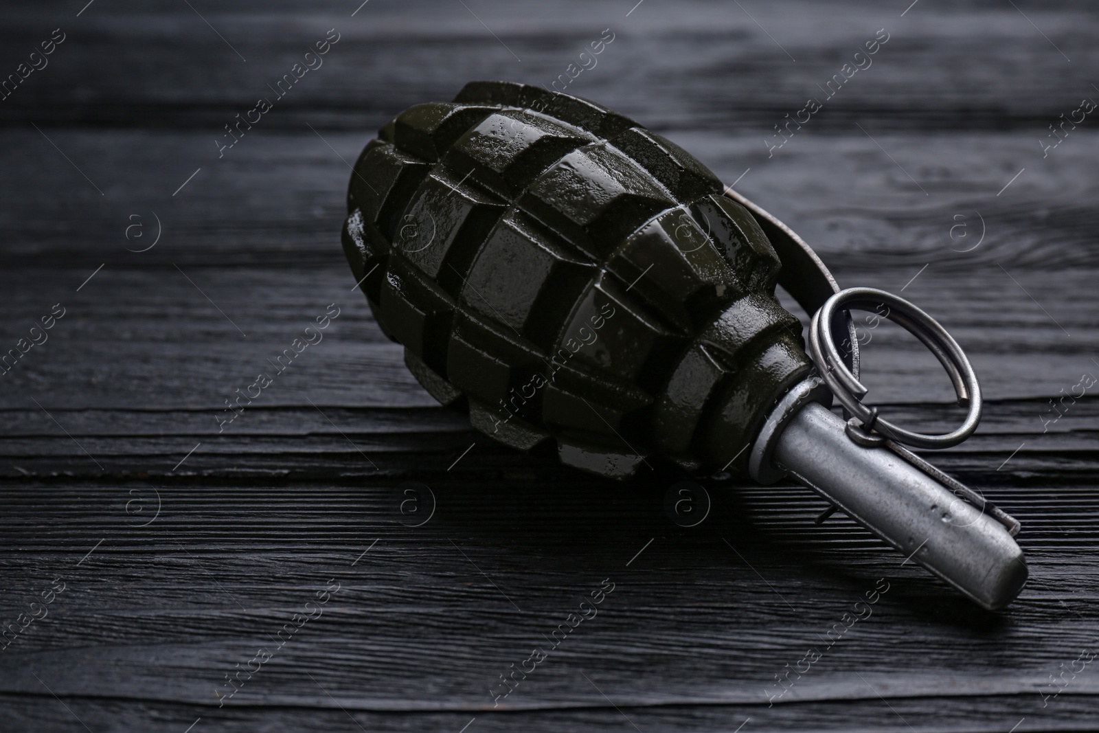 Photo of Hand grenade on black wooden table, closeup. Explosive weapon