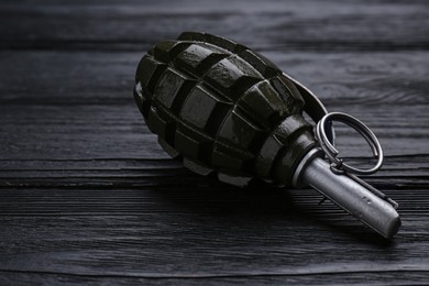Photo of Hand grenade on black wooden table, closeup. Explosive weapon
