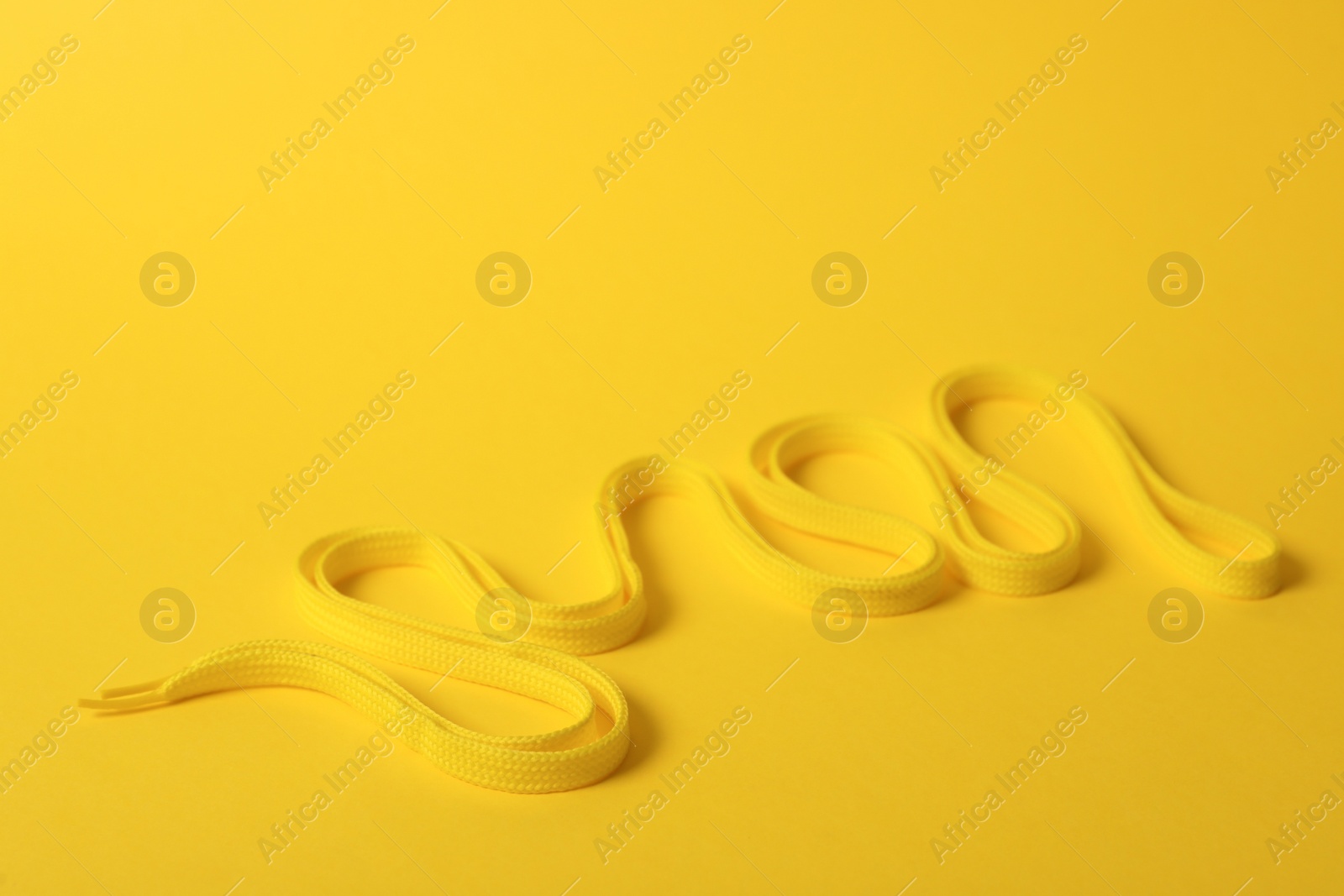 Photo of Shoe lace on yellow background. Space for text