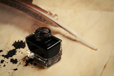 Inkwell with feather on vintage parchments with stains, closeup