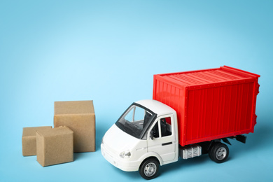 Photo of Toy truck with boxes on blue background, space for text. Logistics and wholesale concept