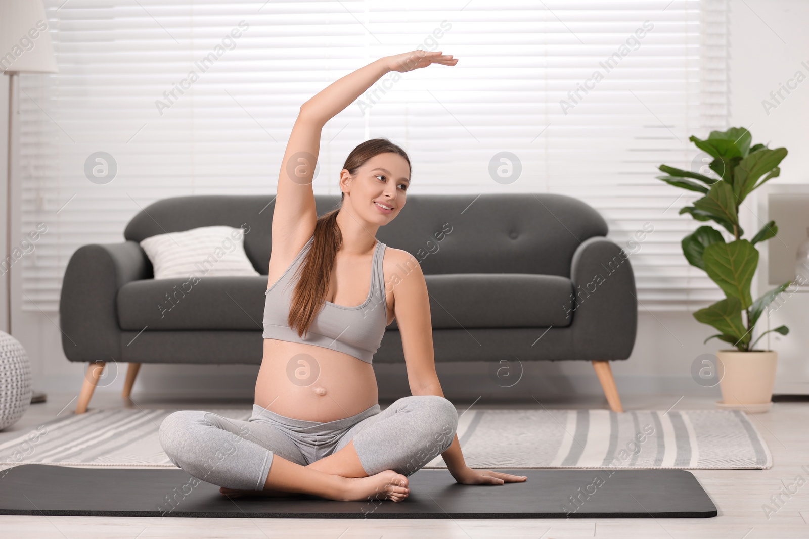 Photo of Pregnant woman doing exercises on yoga mat at home