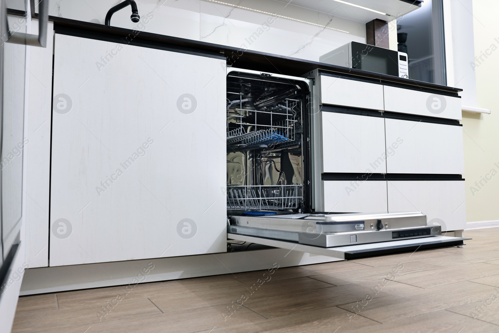 Photo of Open clean empty dishwasher in kitchen, low angle view