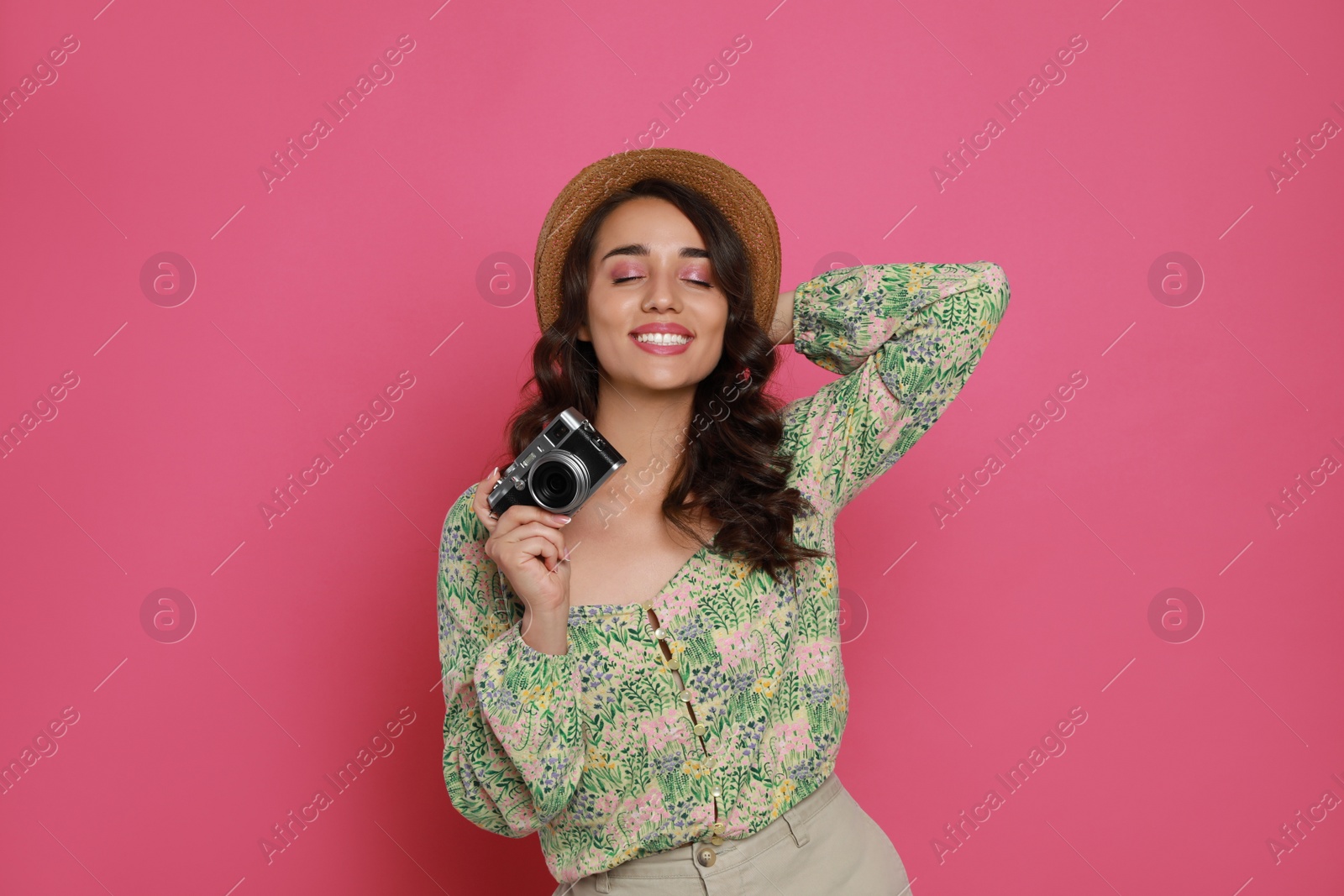 Photo of Beautiful young woman with straw hat and camera on pink background