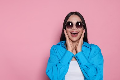 Photo of Attractive happy woman in fashionable sunglasses against pink background. Space for text