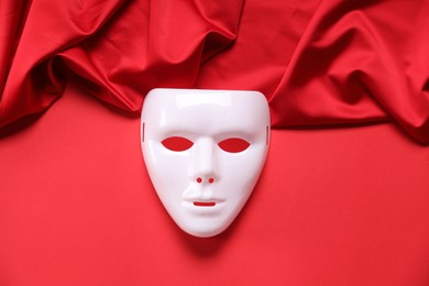 Theater arts. White mask and fabric on red background, top view