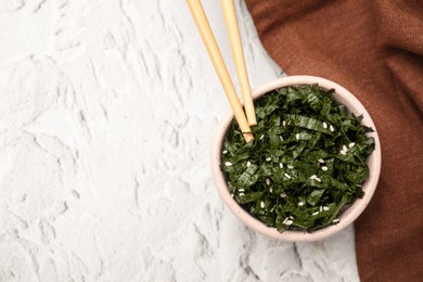 Photo of Chopped nori sheets with sesame and chopsticks on white textured table, flat lay. Space for text