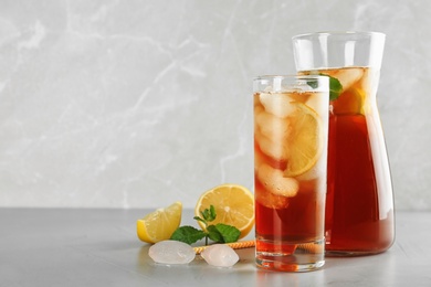 Photo of Refreshing iced tea on grey table against light background. Space for text