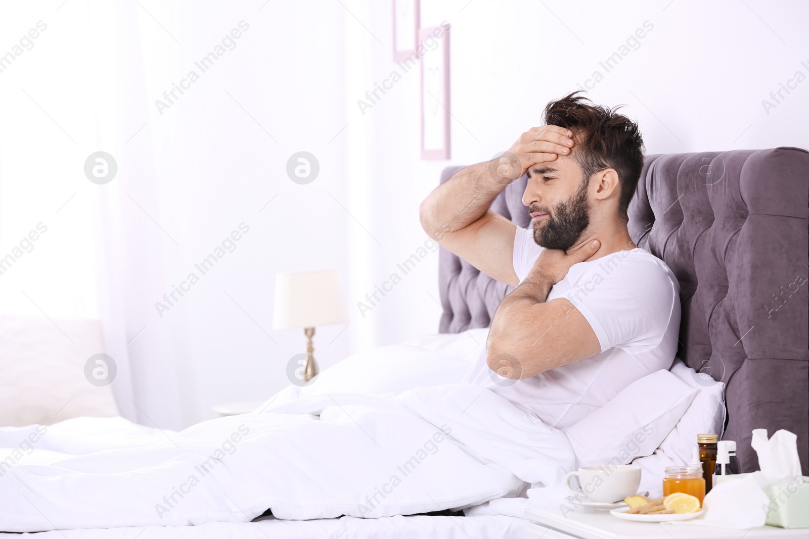 Photo of Ill man suffering from cough in bed. Space for text