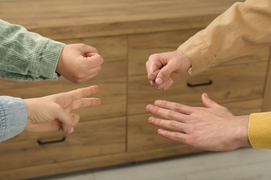 Photo of People playing rock, paper and scissors indoors, closeup