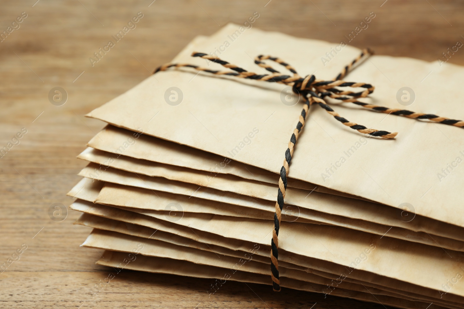 Photo of Stack of old letters tied with string on wooden table, closeup