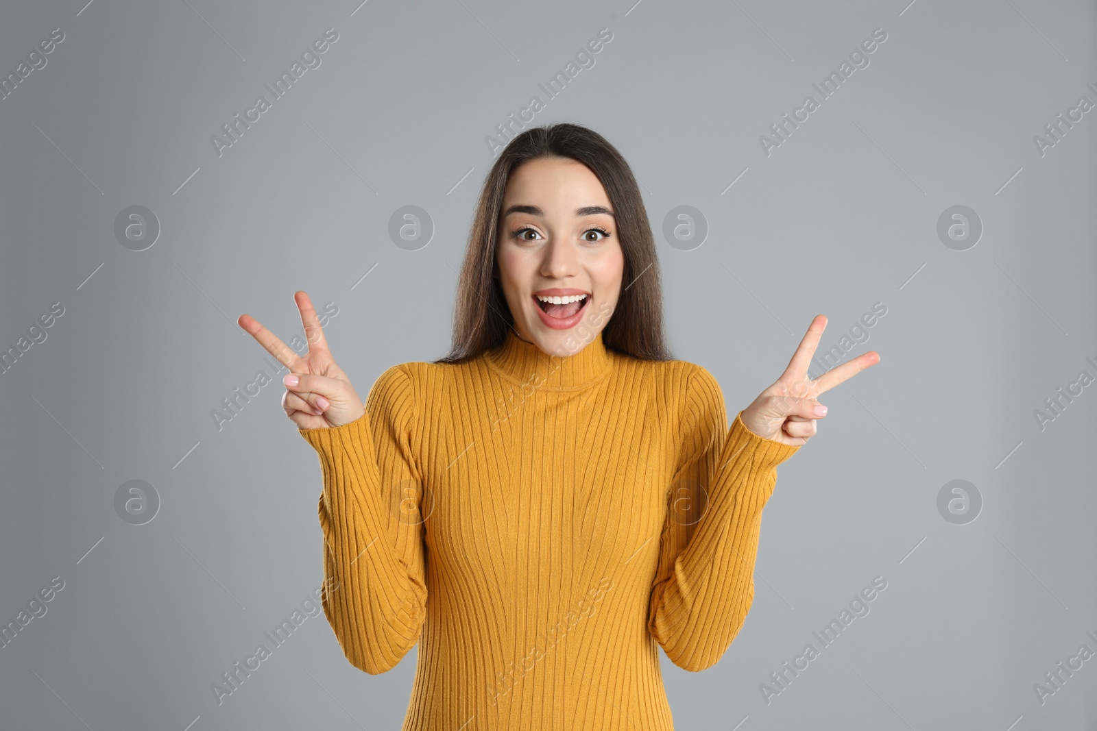 Photo of Woman in yellow turtleneck sweater showing number four with her hands on grey background