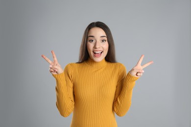 Woman in yellow turtleneck sweater showing number four with her hands on grey background