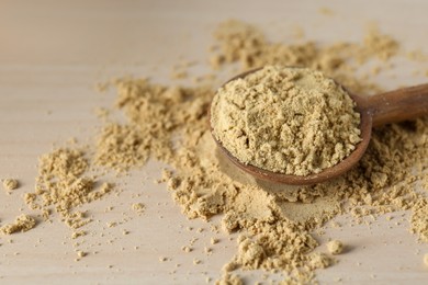 Photo of Spoon with aromatic mustard powder on wooden table, closeup. Space for text