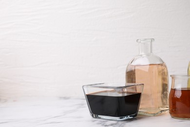 Different types of vinegar on light marble table, closeup. Space for text