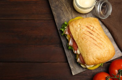 Photo of Delicious sandwich with vegetables, ham and mayonnaise served on wooden table, flat lay. Space for text