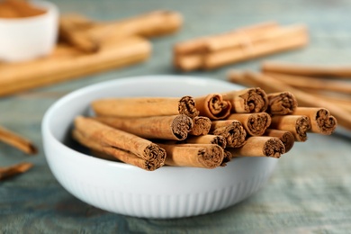 Photo of Aromatic cinnamon sticks on blue wooden table, closeup
