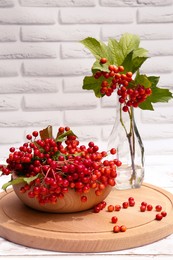 Composition with ripe red viburnum berries on white wooden table