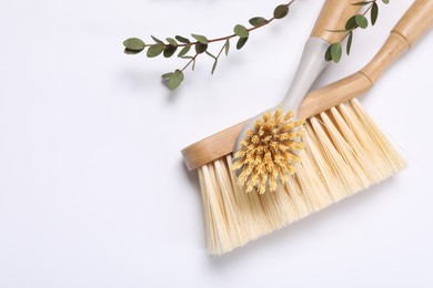 Photo of Cleaning brushes and eucalyptus leaves on white background, top view. Space for text