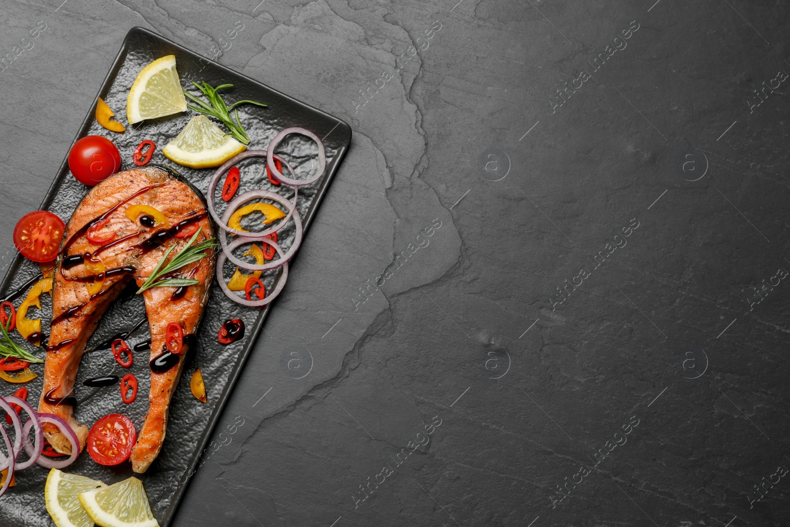 Photo of Tasty salmon steak served on black table, top view. Space for text