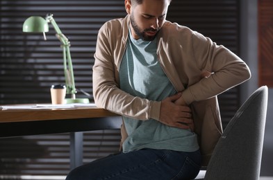 Photo of Man suffering from back pain in office, closeup. Bad posture problem