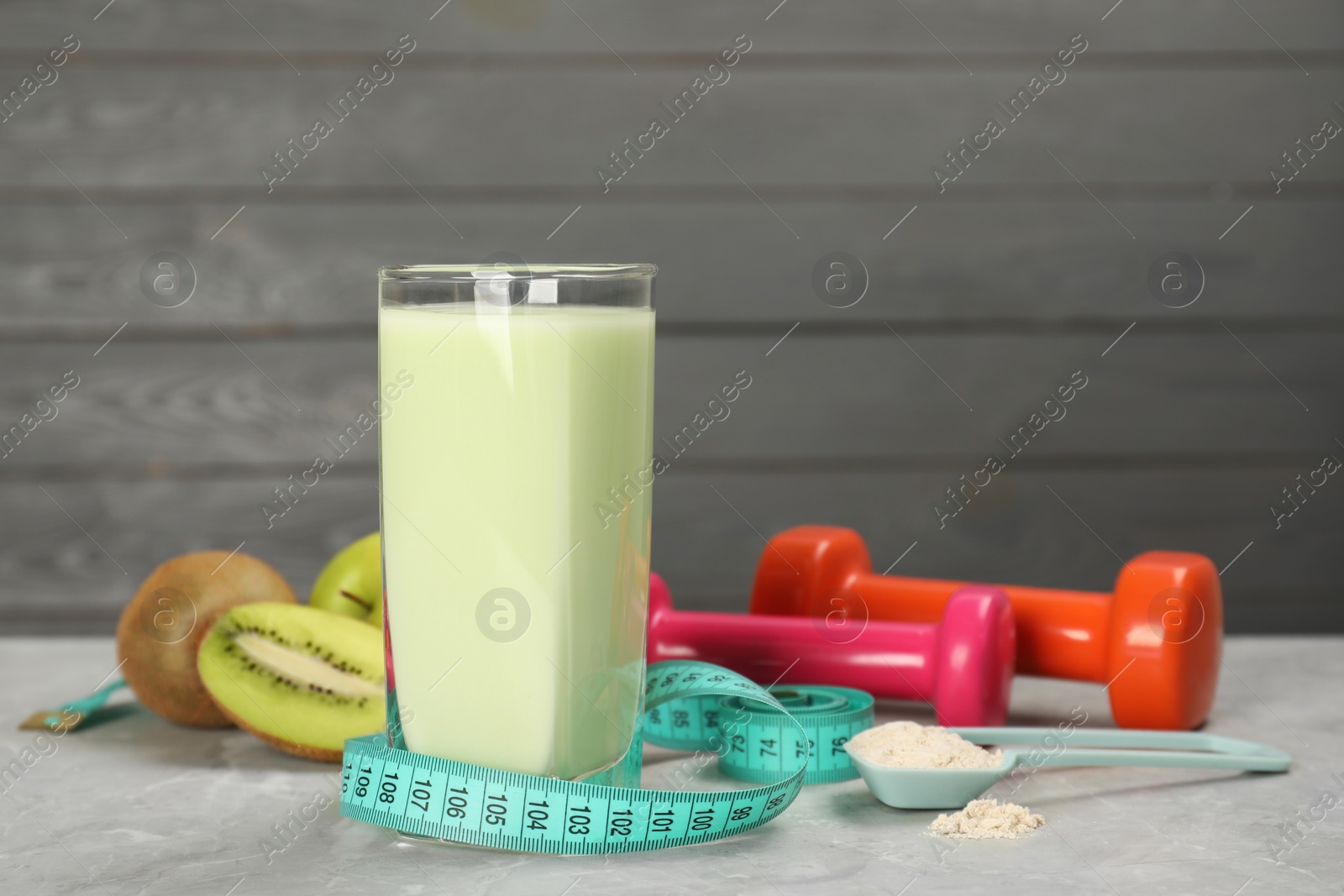 Photo of Tasty shake, measuring tape, powder, fruits and dumbbells on light gray marble table, space for text. Weight loss