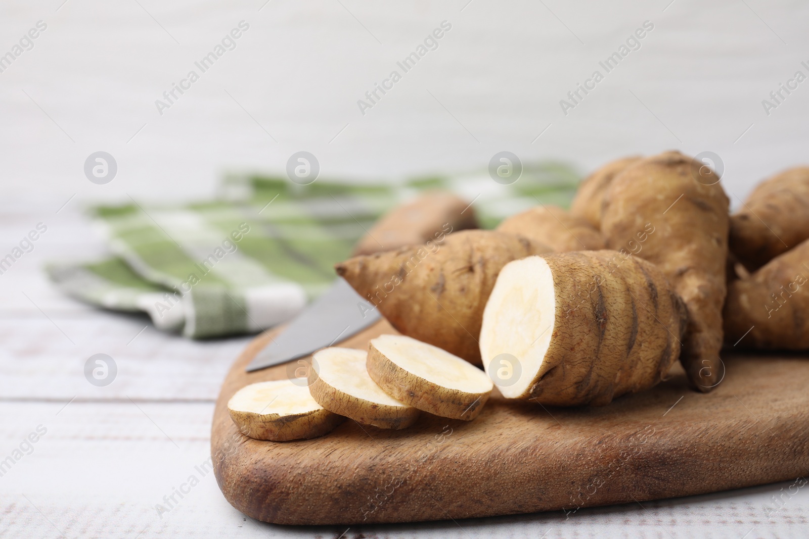 Photo of Whole and cut turnip rooted chervil tubers on light wooden table, closeup. Space for text