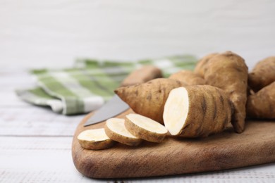 Whole and cut turnip rooted chervil tubers on light wooden table, closeup. Space for text