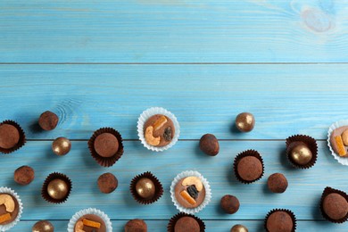 Different delicious chocolate candies on light blue wooden table, flat lay. Space for text