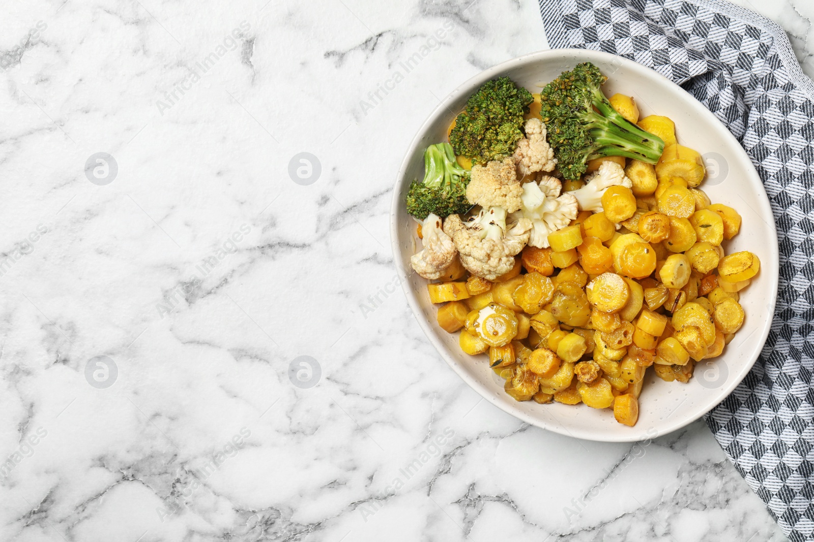 Photo of Baked yellow carrot with broccoli and cauliflowers on white marble table, top view. Space for text