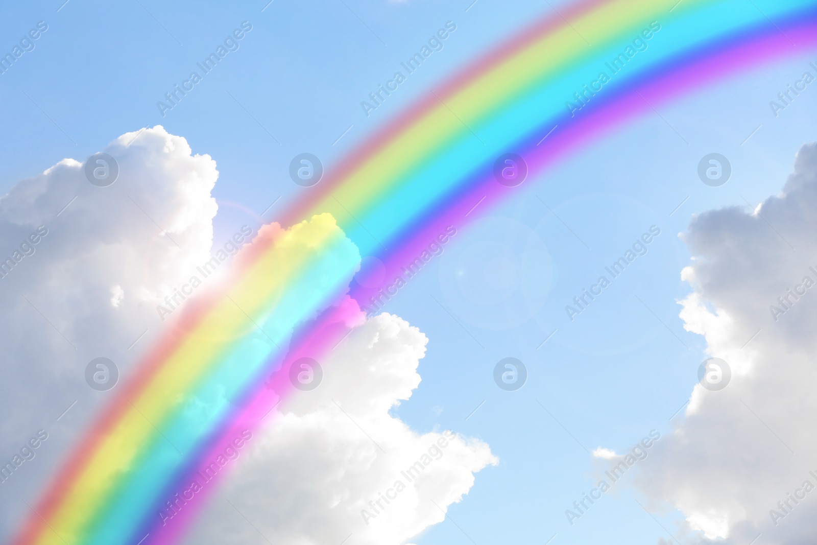 Image of Beautiful view of bright rainbow in blue sky on sunny day