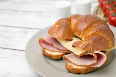 Photo of Tasty crescent roll with ham and cheese on white wooden table, closeup