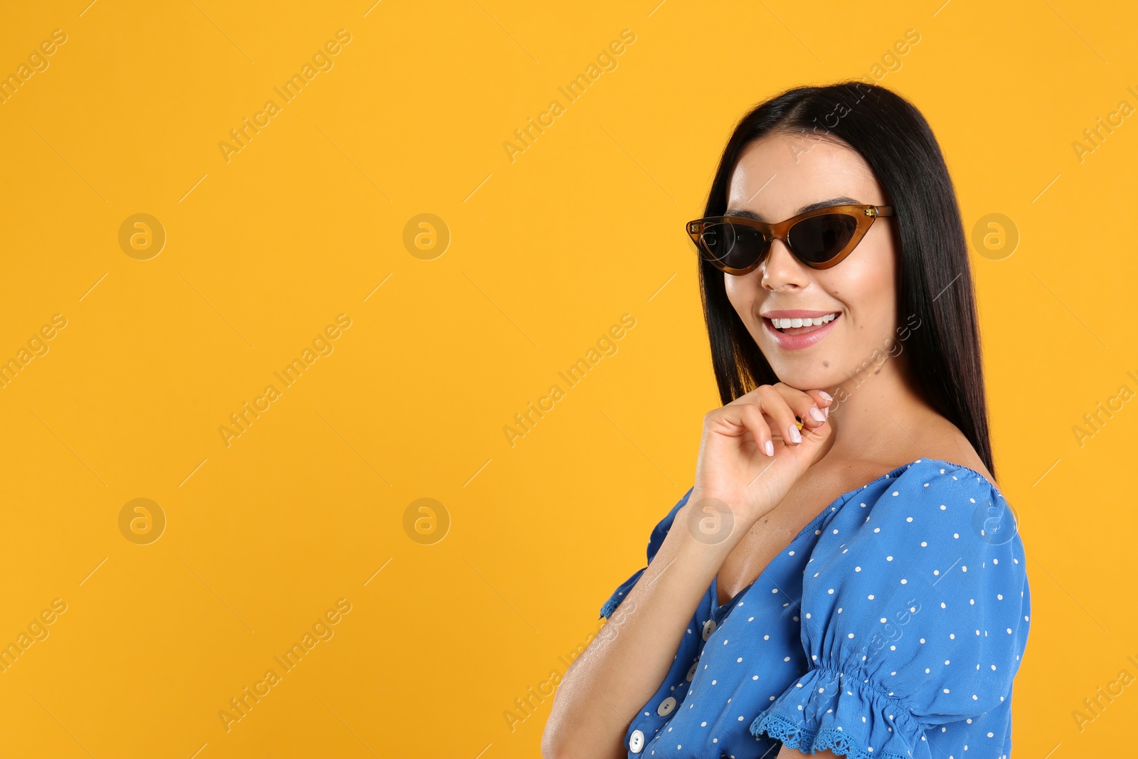 Photo of Beautiful woman wearing sunglasses on yellow background. Space for text