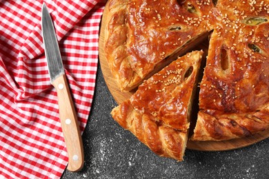 Photo of Cut delicious homemade pie and knife on black table, flat lay