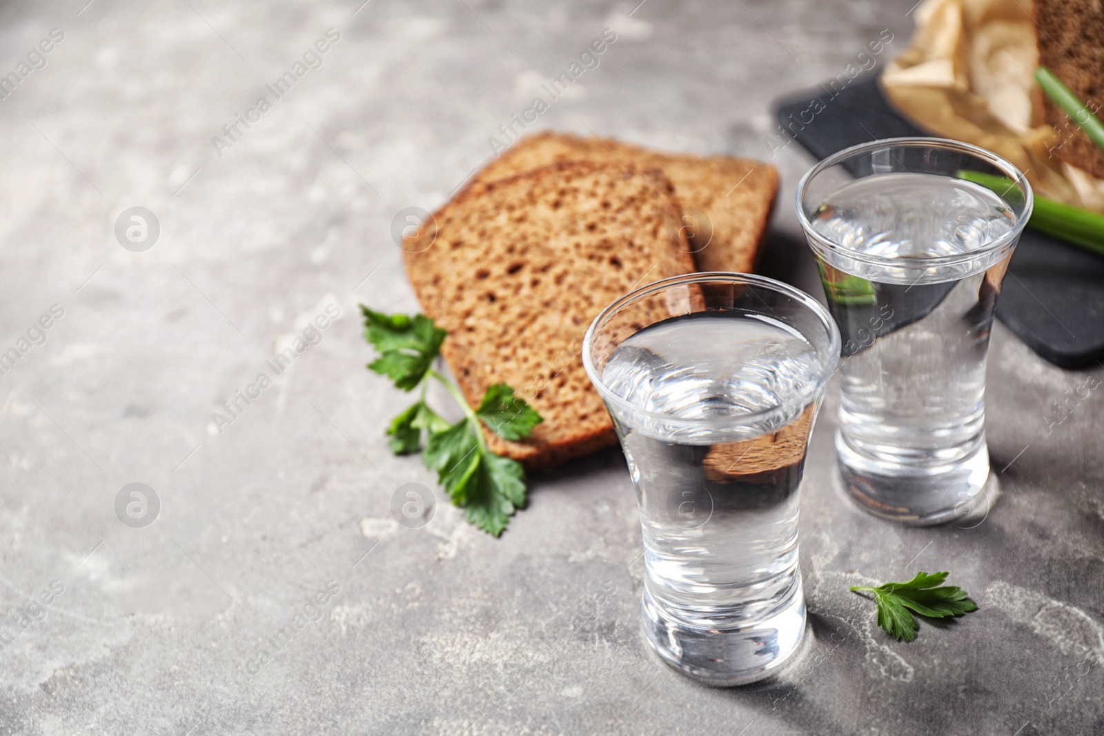 Photo of Cold Russian vodka with snacks on grey table, closeup