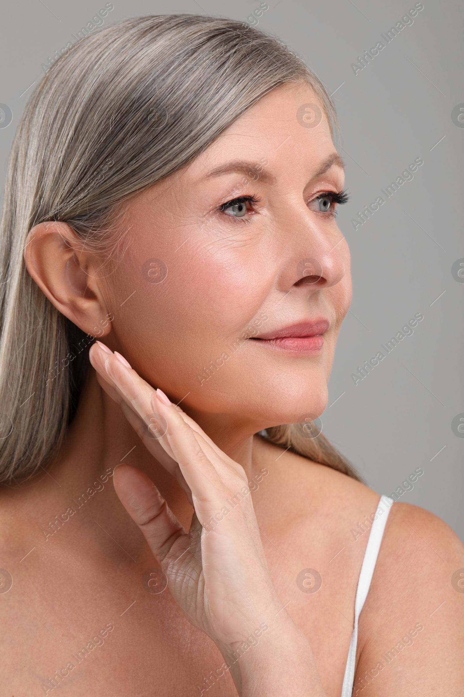 Photo of Beautiful mature woman with healthy skin on gray background