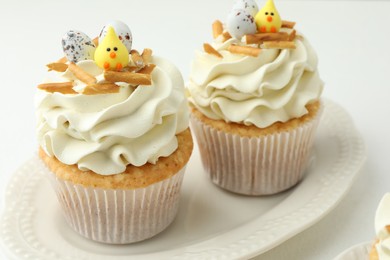 Photo of Tasty Easter cupcakes with vanilla cream on white table, closeup