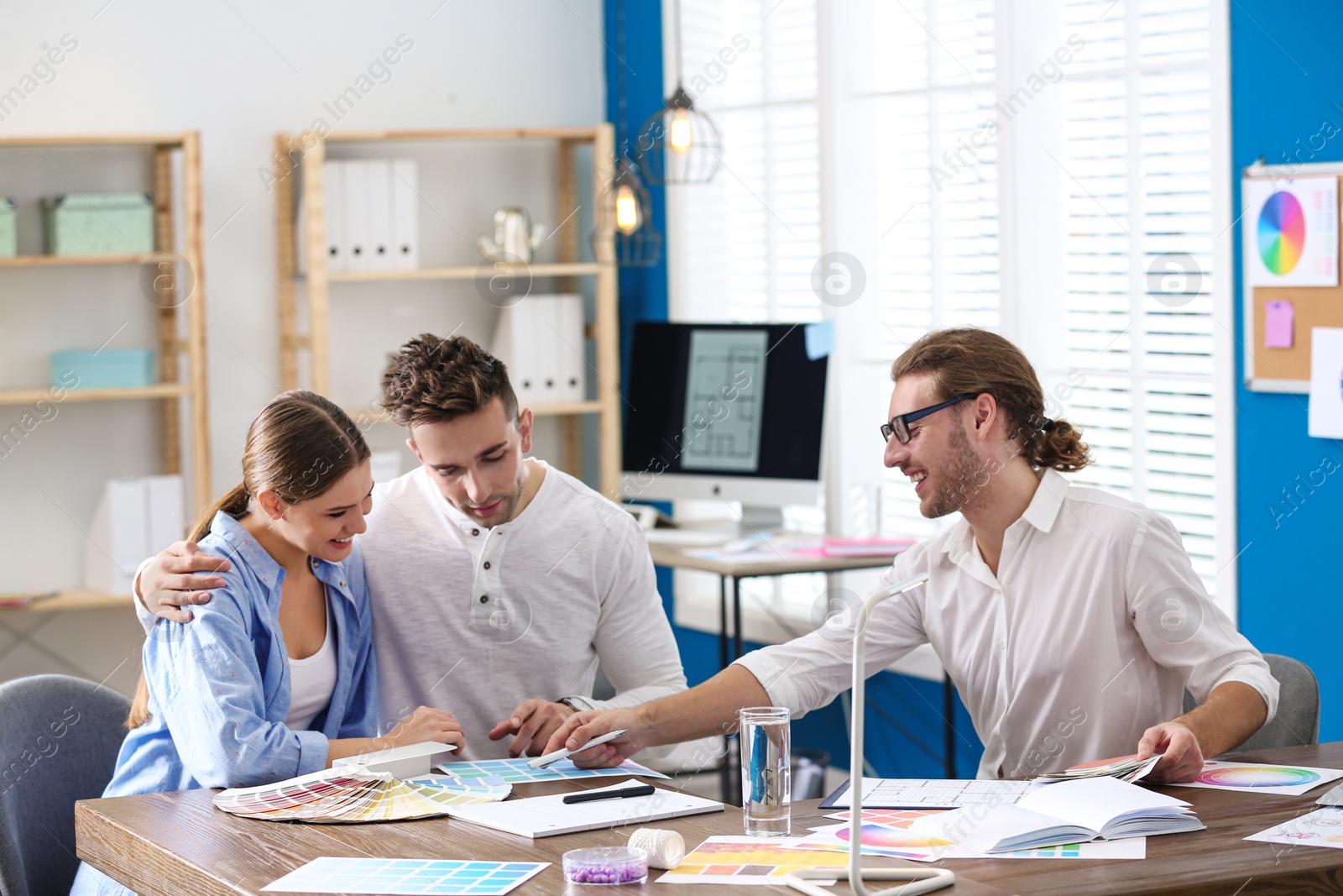 Photo of Interior designer consulting young couple in office