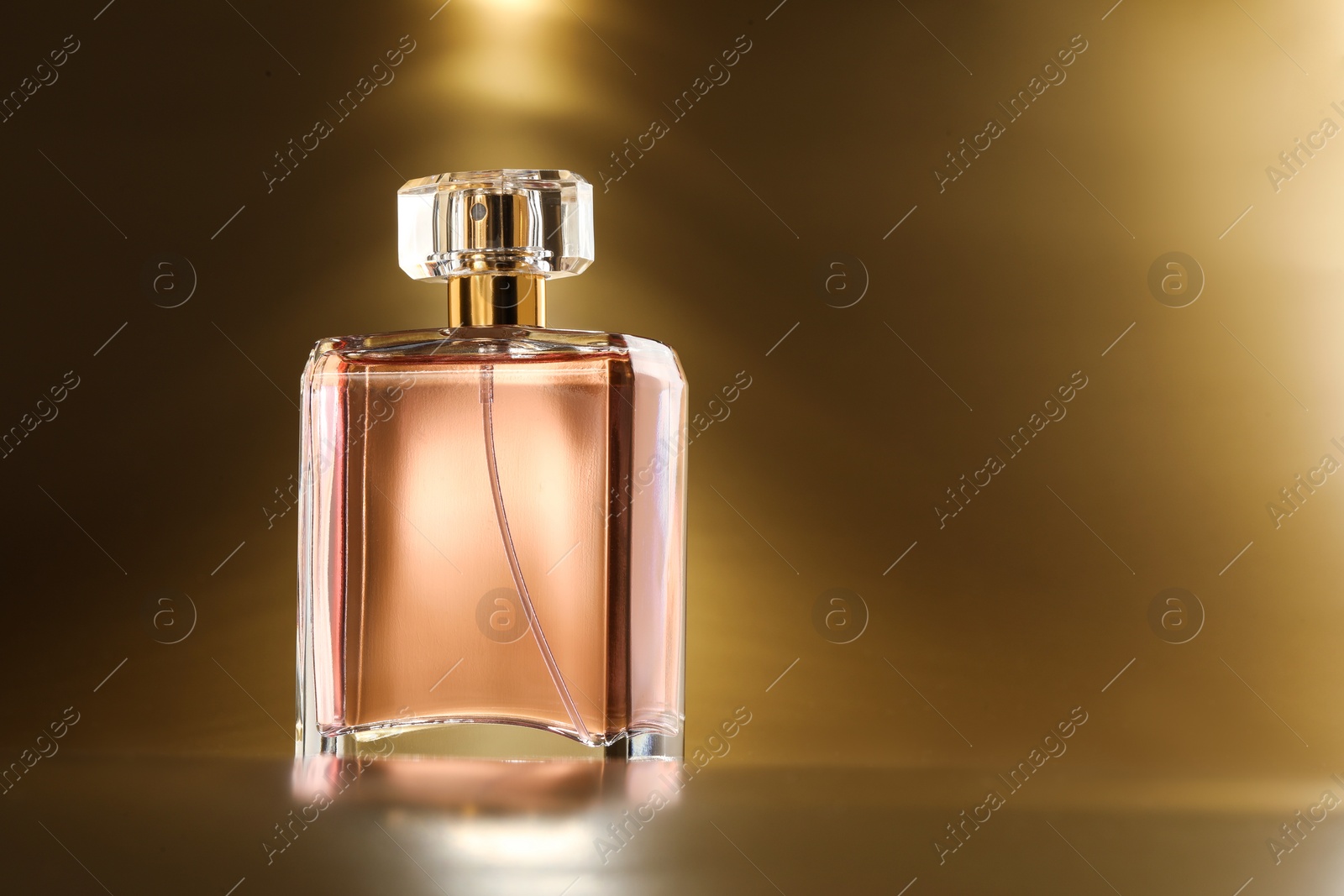 Photo of Luxury women's perfume. Sunlit glass bottle on golden background, space for text