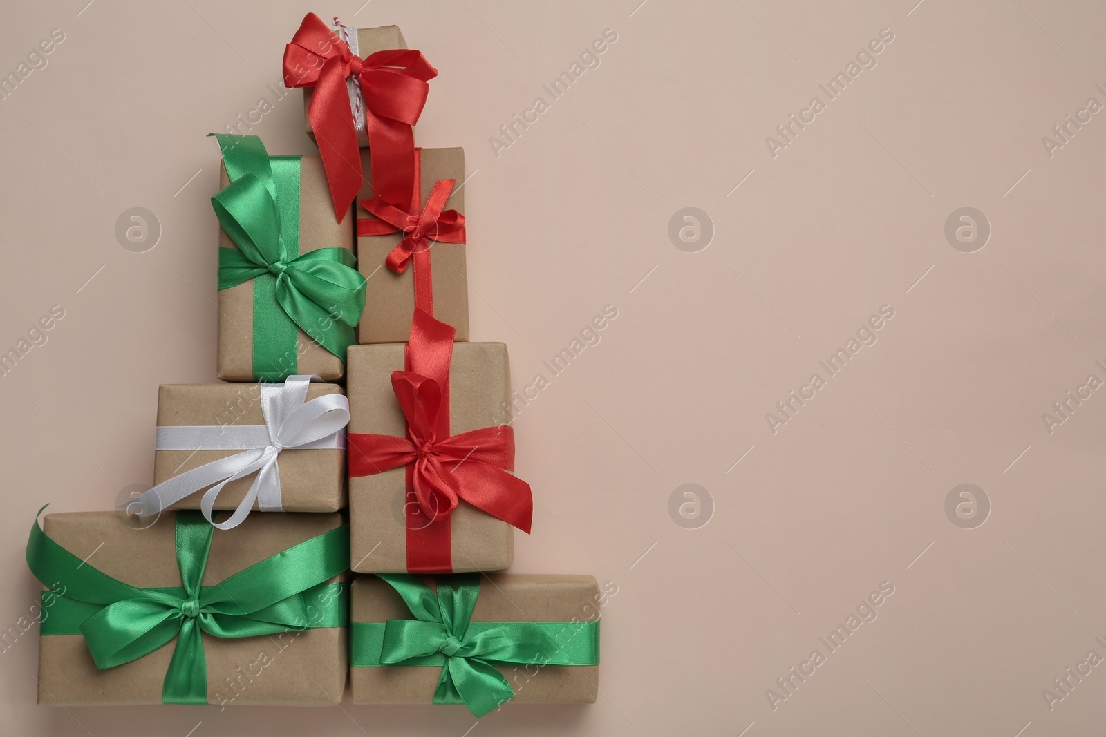 Photo of Christmas tree shape of gift boxes on beige background, flat lay. Space for text