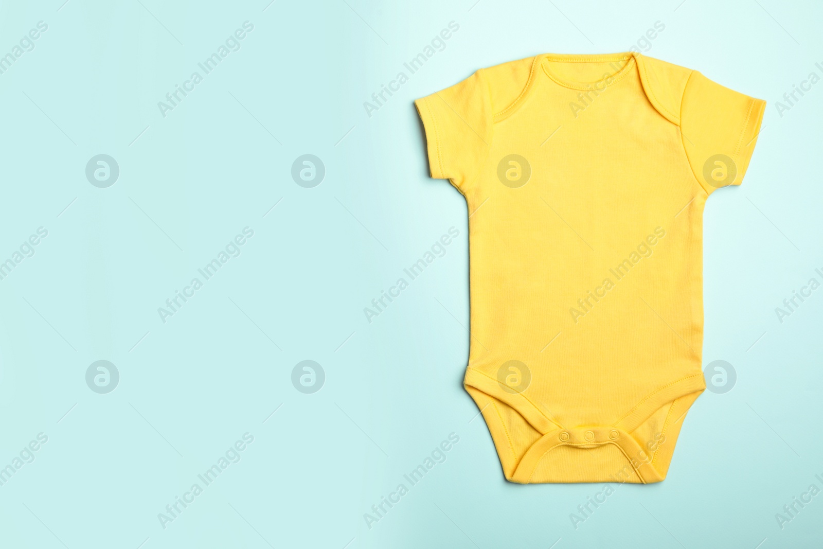 Photo of Child's bodysuit on light blue background, top view. Space for text