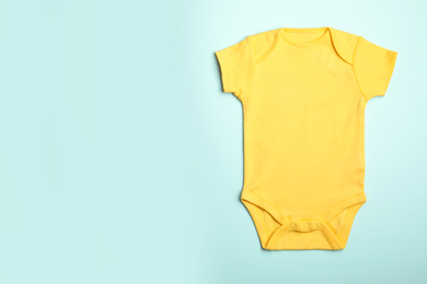 Photo of Child's bodysuit on light blue background, top view. Space for text