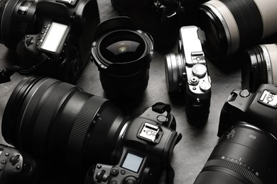 Photo of Modern cameras on dark gray table, closeup
