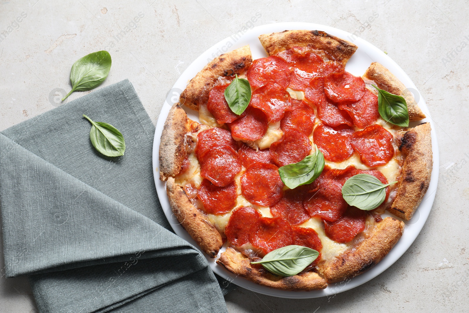 Photo of Tasty pepperoni pizza with basil on grey table, top view