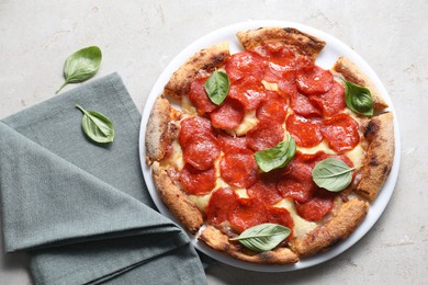 Tasty pepperoni pizza with basil on grey table, top view