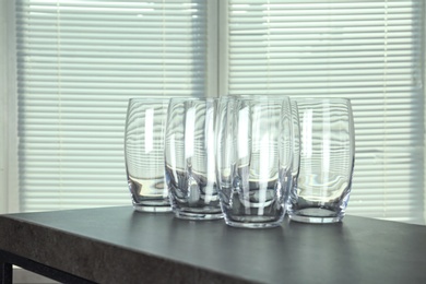 Photo of Empty glasses on grey table against blurred background, space for text