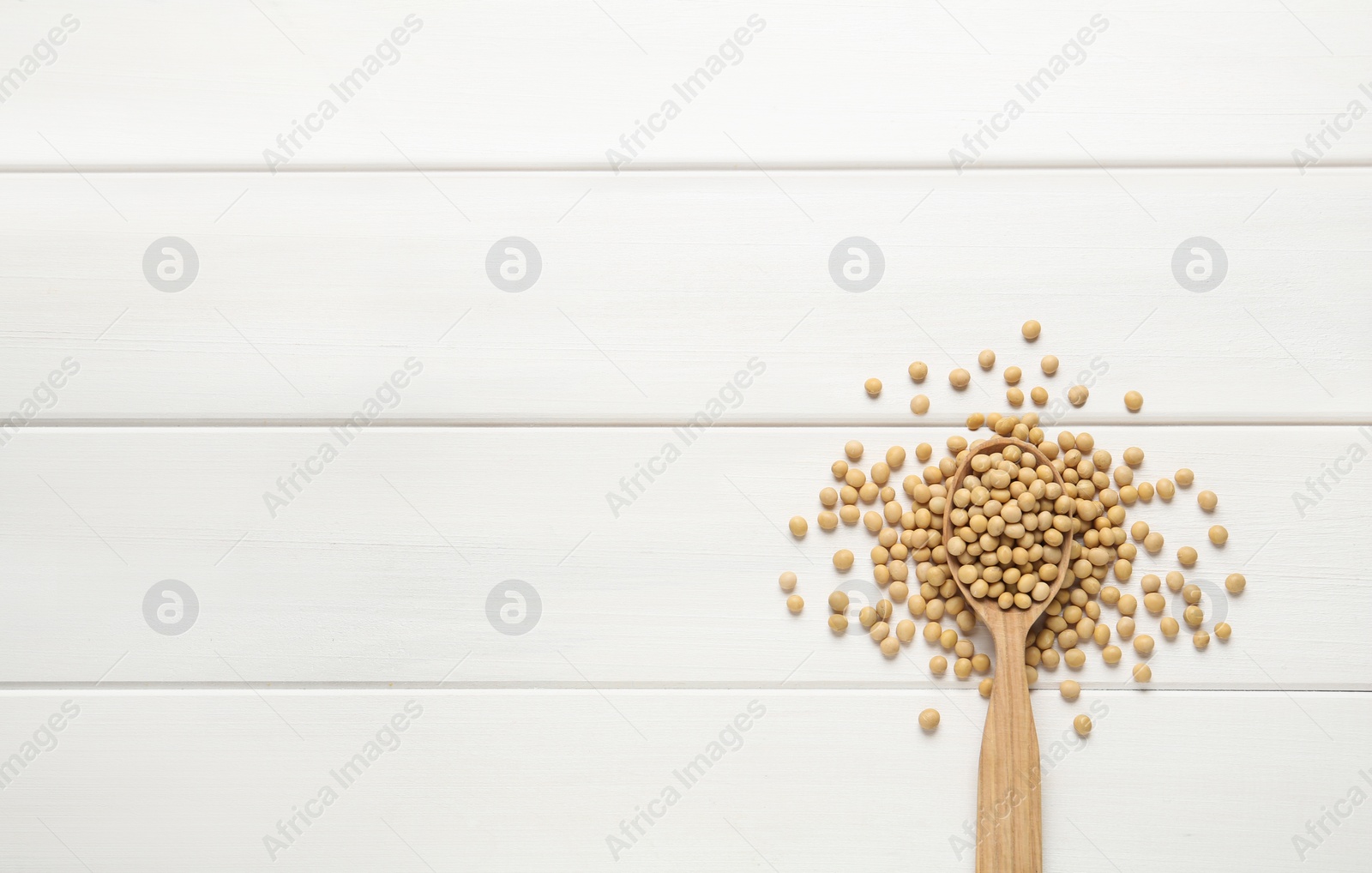 Photo of Spoon with soy on white wooden table, flat lay. Space for text
